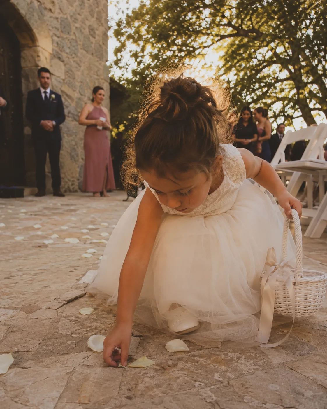 Petite fille en robe blanche lançant des pétales